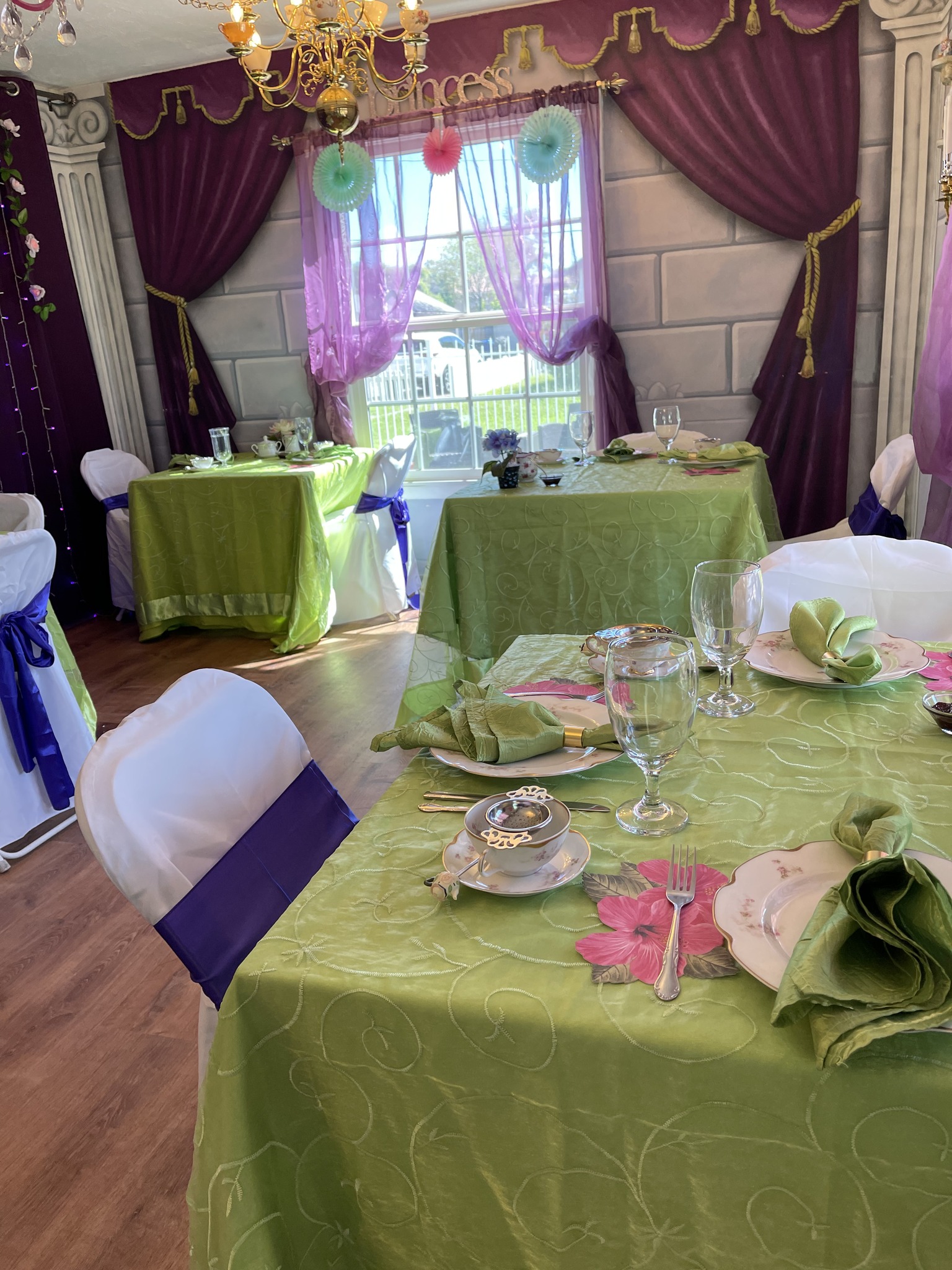 Tea tables set with green linens and place settings inside Mrs. Potts Tea Party